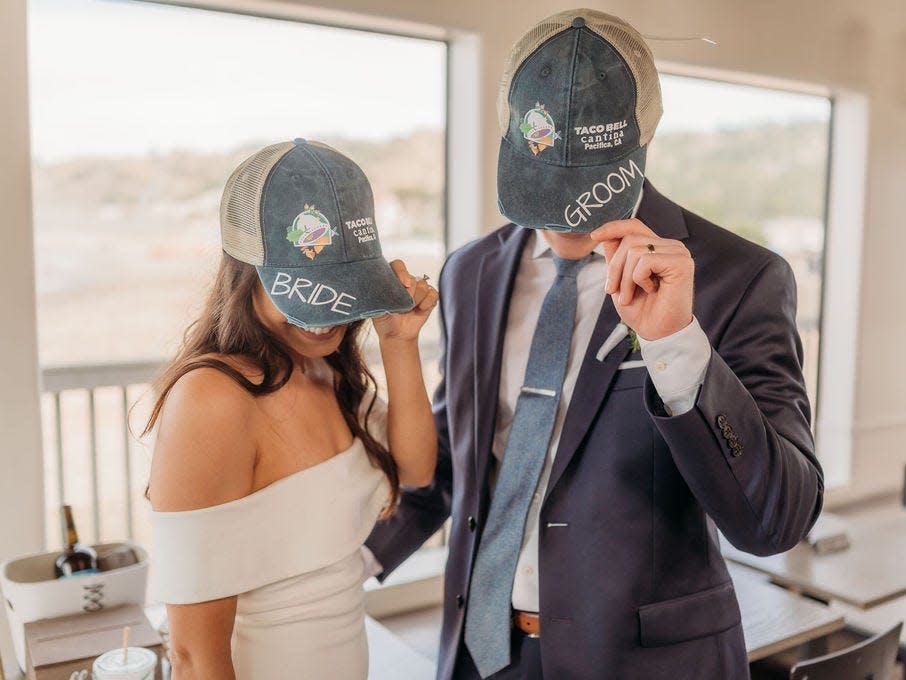 A couple wears Taco Bell hats at their wedding reception.