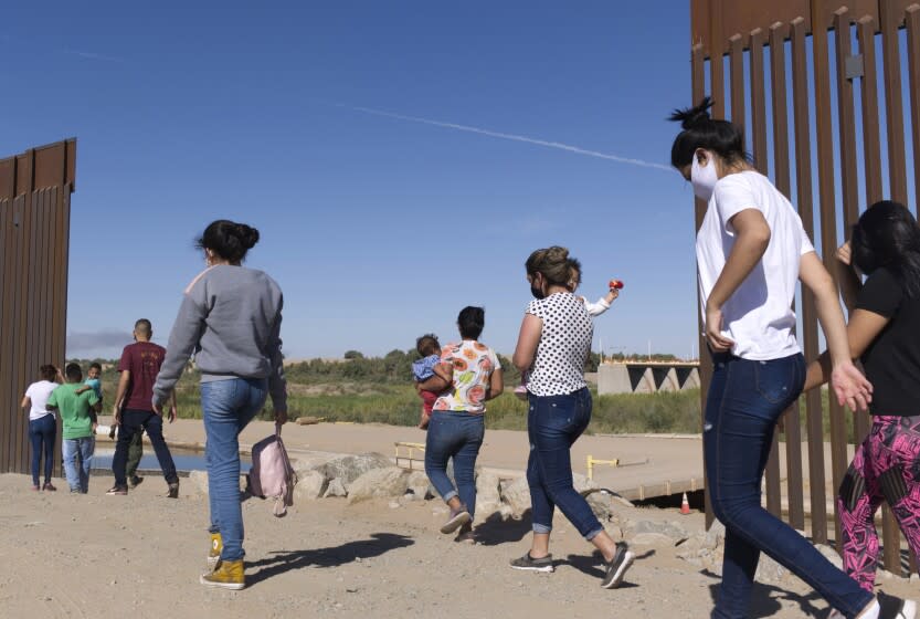 Un grupo de migrantes brasileños cruza por una apertura en la frontera entre Estados Unidos y México, el lunes 8 de junio de 2021, en Yuma, Arizona, para solicitar asilo en Estados Unidos. (AP Foto/Eugene Garcia, archivo)