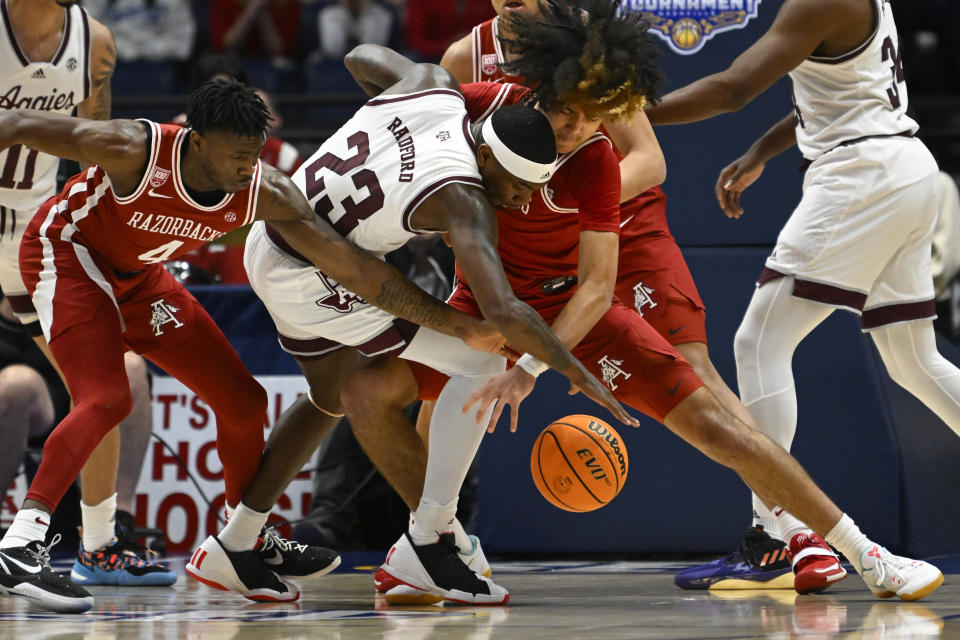 Texas A&M guard Tyrece Radford (23), Arkansas guard Davonte Davis (4) and guard Anthony Black (0) vie for the ball during the first half of an NCAA college basketball game in the quarterfinals of the Southeastern Conference Tournament, Friday, March 10, 2023, in Nashville, Tenn. (AP Photo/John Amis)
