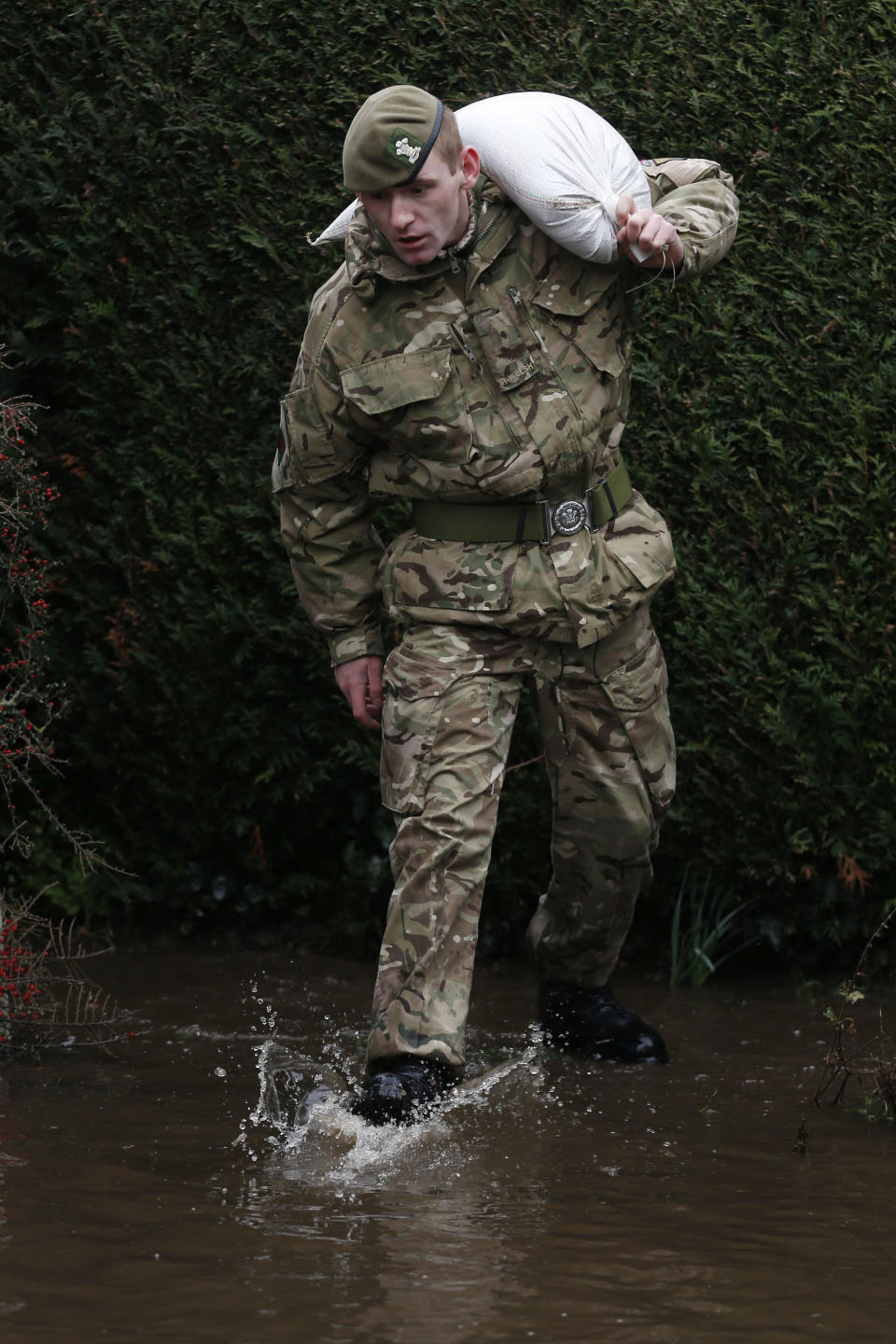 British army soldier carries a sand bag as troops work to help protect homes from rising flood waters at Chertsey, England, Wednesday, Feb. 12, 2014. The River Thames has burst its banks after reaching its highest level for many years, flooding riverside towns upstream of London, including Chertsey which is about 30 miles west of central London. Some hundreds of troops have been deployed to assist with flood protection and to get medical assistance to the sick and vulnerable.(AP Photo/Sang Tan)