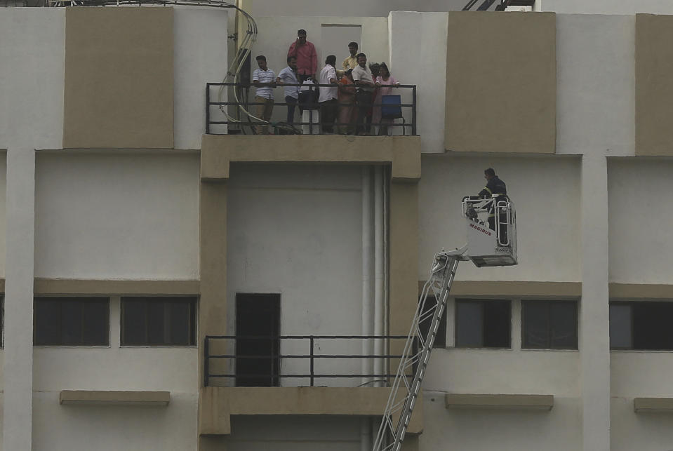 People awaiting rescue stand near the balcony of a nine-story building with offices of a state-run telephone company during a fire in Mumbai, India, Monday, July 22, 2019. (AP Photo/Rafiq Maqbool)