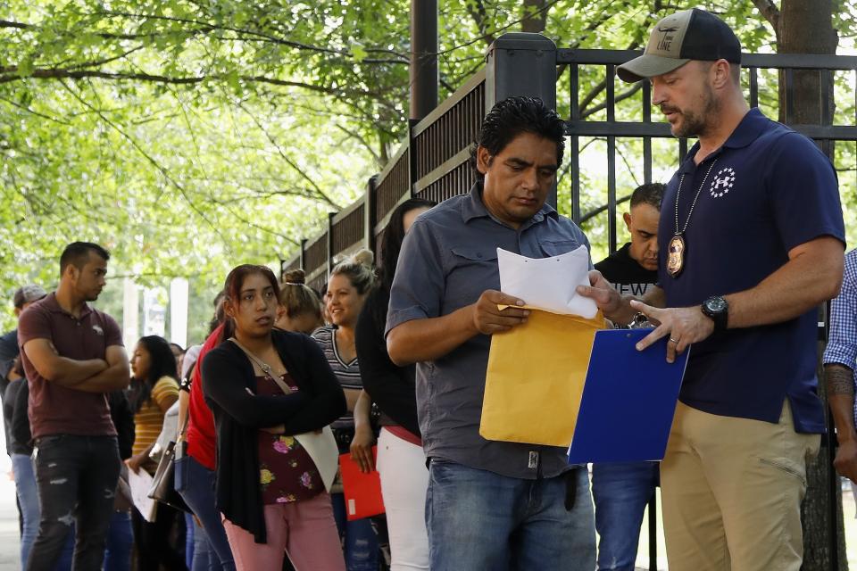 In this June 12, 2019, photo, an Immigration and Customs Enforcement official gives direction to a person outside the building that houses ICE and the immigration court in Atlanta. Immigration attorneys say the new timetable is too fast to prepare cases. The government has a goal of completing 56,000 cases in 10 cities in a year. (AP Photo/Andrea Smith)