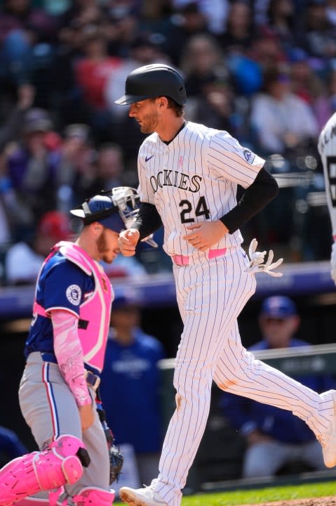 Colorado Rockies' Ryan McMahon (24) crosses home plate after being forced in on a bases-loaded walk to Brenton Doyle as Texas Rangers catcher Jonah Heim, left, looks on in the eighth inning of a baseball game Sunday, May 12, 2024, in Denver. (AP Photo/David Zalubowski)