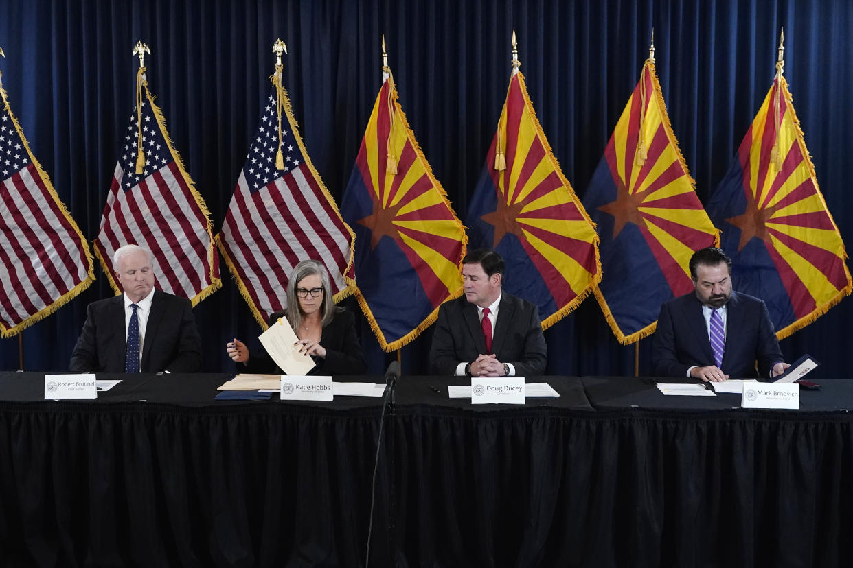 Arizona Democrat governor-elect and current Arizona Secretary or State Katie Hobbs, second from left, signs the official certification for the Arizona general election canvass in a ceremony as Arizona Republican Gov. Doug Ducey, second from right, Arizona Supreme Court Chief Justice Robert Brutinel, left, and Arizona Attorney General Mark Brnovich flank Hobbs at the Arizona Capitol in Phoenix, Monday, Dec. 5, 2022. (AP Photo/Ross D. Franklin, Pool)