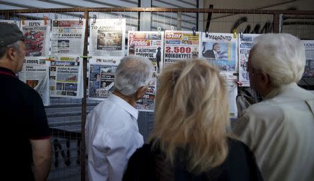 People read newspapers hanging outside a kiosk in Omonia Square in central Athens, Greece, September 19, 2015. REUTERS/Paul Hanna