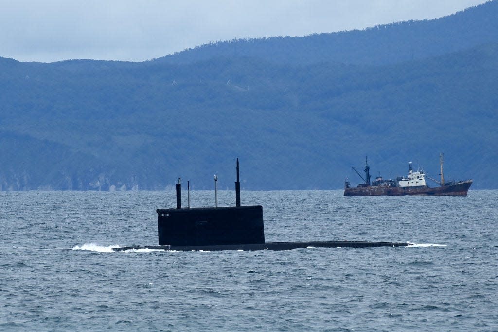 A Russian submarine near a boat near the coast