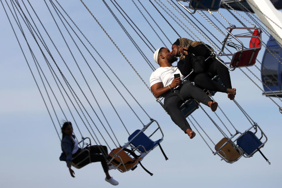 Arif El-Boukari, left and Buthaina Ali, from Detroit, shares a kiss while riding the wave swinger during their Eid Al Fitr holiday, Friday, May 14, 2021 in Navy Pier, Chicago. The U.S. Centers for Disease Control and Prevention eased its guidelines on the wearing of masks outdoors, saying fully vaccinated Americans don't need to cover their faces anymore unless they are in a big crowd of strangers. (AP Photo/Shafkat Anowar)