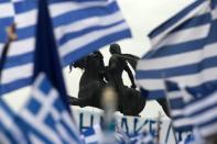 A statue of Alexander the Great is seen through waving Greek national flags during a rally against the use of the term "Macedonia" in any solution to a dispute between Athens and Skopje over the former Yugoslav republic's name, in the northern city of Thessaloniki, Greece, January 21, 2018. REUTERS/Alexandros Avramidis