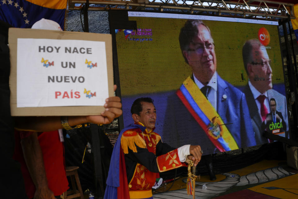 Supporters of Colombia's new President Gustavo Petro watch on a giant TV screen his swearing-in ceremony in San Antonio, on the Venezuelan border with Colombia, Sunday, Aug. 7, 2022. (AP Photo/Matias Delacroix)