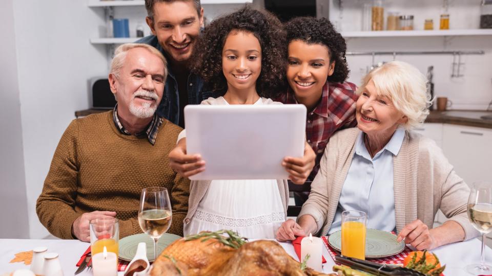 Selective focus of african american girl holding digital tablet near parents during thanksgiving celebration.