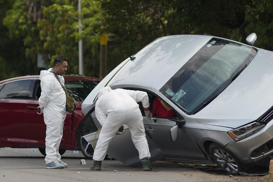 Forensic medical examiners work at the scene where an unidentified man was killed in Apatzingan, Mexico, Sunday, July 2, 2023. Apatzingan, the regional hub where the area's agricultural products are traded, gunmen carjacked a family, took their auto at gunpoint and used it to shoot another driver to death just a few blocks away. (AP Photo/Eduardo Verdugo)
