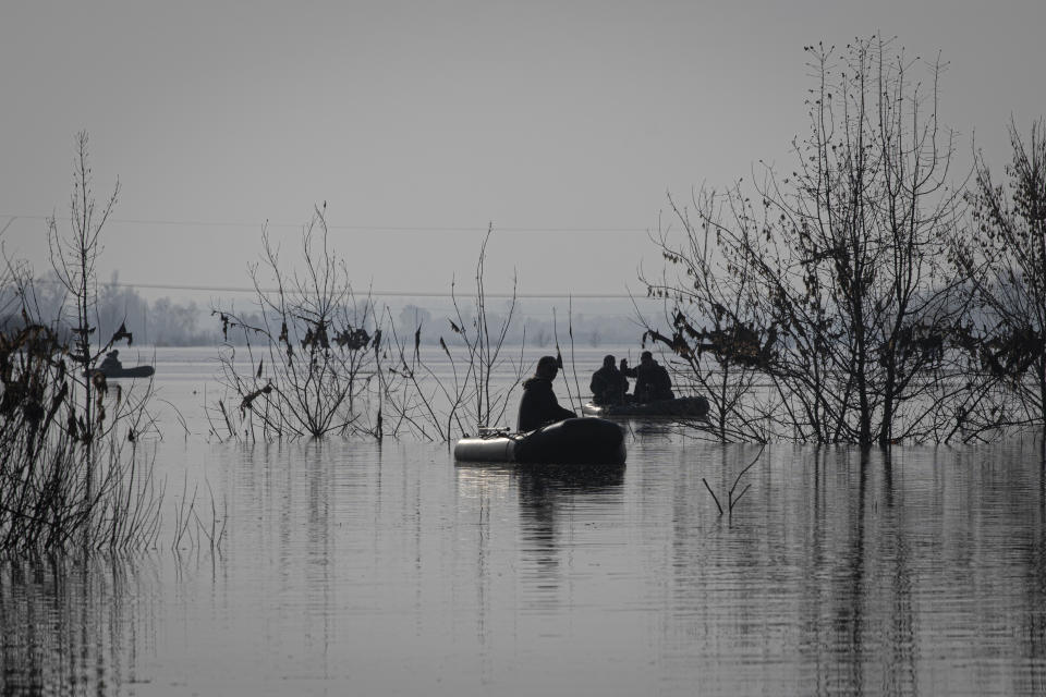 People fish in a flooded area in the village of Demydiv, about 40 kilometers (24 miles) north of Kyiv, Ukraine, Tuesday, Nov. 2, 2022. After the flood in Demydiv, residents said their tap water turned cloudy, tasted funny and left a film on pots and pans after cooking. The village was under Moscow's control until April, when Russian troops withdrew after failing to take the capital. (AP Photo/Andrew Kravchenko)