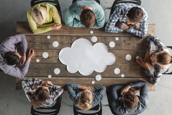 A group of workers sit around a cutout of a cloud.