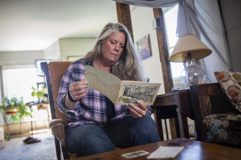 Lisa Edson Neveu, 52, reads a brochure at her house in Montpelier, Vt., July 3, 2024. A year after catastrophic flooding inundated parts of Vermont, some homeowners are still in the throes of recovery. (AP Photo/ Dmitry Belyakov)