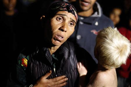 Bulgarian Roma Sashka Ruseva (L), 38, holds her son Atanas, 2, as she speaks to media outside her house in the town of Nikolaevo, some 280km (173miles) east of Sofia October 24, 2013. REUTERS/Stoyan Nenov