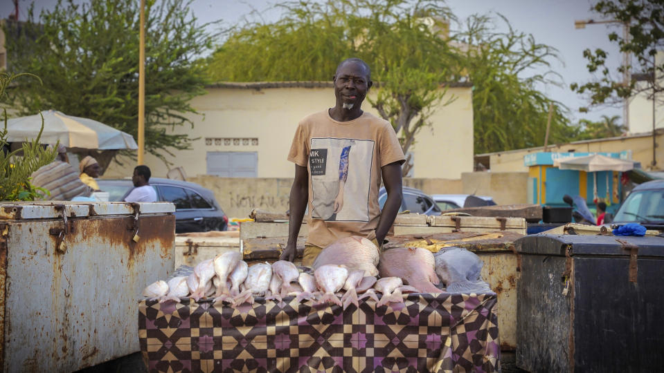 A fishmonger stands in front of his wares near the Soumbedioune fish market in Dakar, Senegal, May 31, 2022. The lack of grouper has also made other fish more expensive, according to nutritionist Codou Kébé. Kébé placed the blame squarely on overfishing, which she said has robbed the nation of the generations-old food resource. (AP Photo/Grace Ekpu)