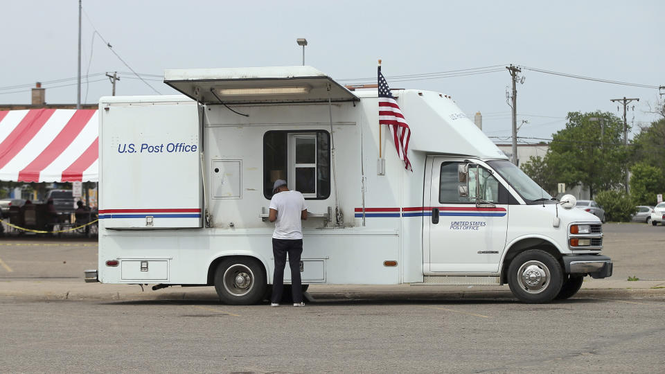 A customer visits a mobile post office in a parking lot Thursday, June 18, 2020 in Minneapolis, set up to help fill the service gap left by two postal facilities destroyed in the unrest following the death of George Floyd. Floyd died in police custody after video shared online by a bystander showed former officer Derek Chauvin kneeling on Floyds' neck during his arrest as he pleaded that he couldn't breathe. (AP Photo/Jim Mone)