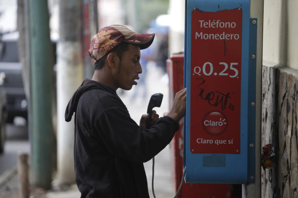 A Honduran migrant uses a public phone outside the "Casa del Migrante" shelter, after arriving to Guatemala City, Wednesday, Oct. 17, 2018. The group of some 2,000 Honduran migrants hit the road in Guatemala again Wednesday, hoping to reach the United States despite President Donald Trump's threat to cut off aid to Central American countries that don't stop them. (AP Photo/Moises Castillo)