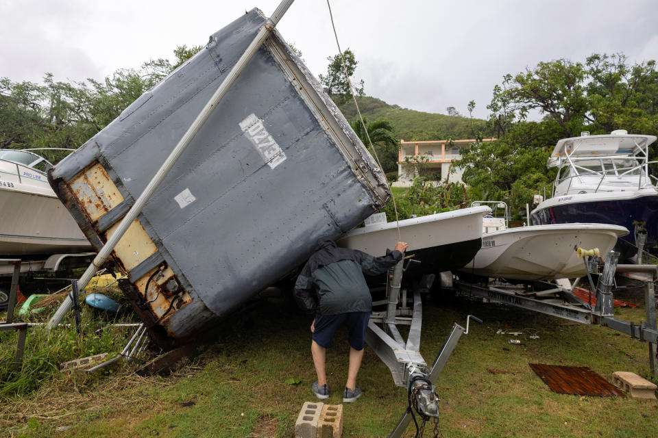 Um homem inspeciona os danos em seu barco depois que um trailer tombou.