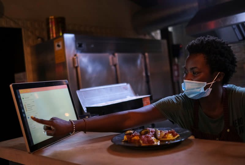 An employee using the "Funky Pay" app informs clients that their order is ready, at Funky Pizza restaurant, where the app replaces waiters, in Palafrugell