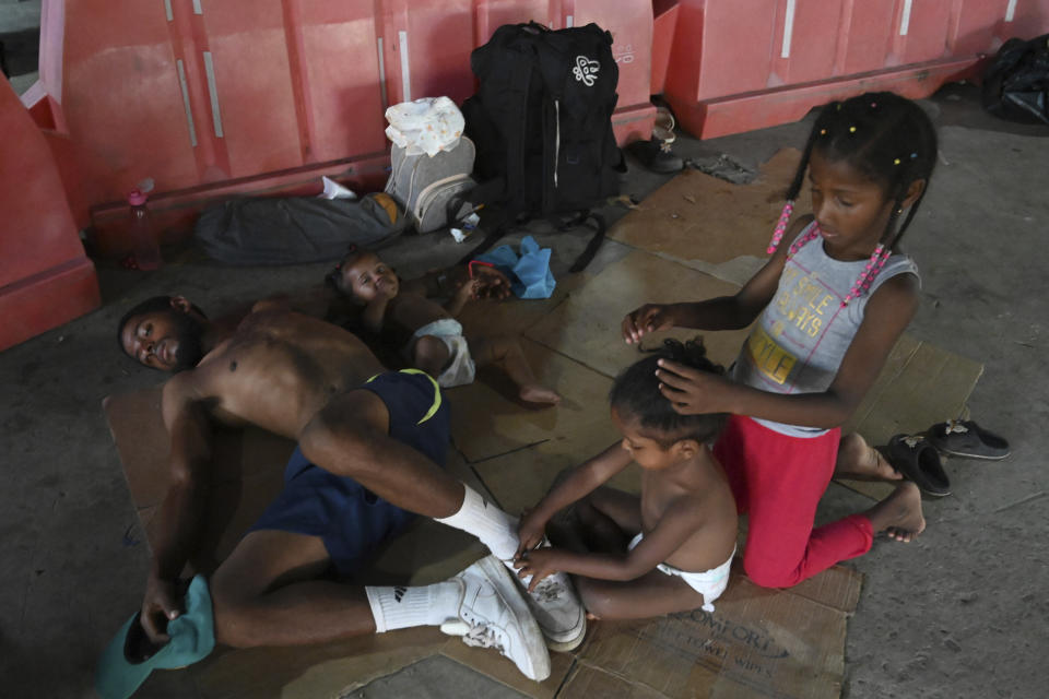 A migrant family rests on the ground at a Migrant Temporal Attention Center, as they wait for transportation to continue on their way north to Nicaragua and hopefully to the Mexico-United States border, in Paso Canoas, Costa Rica, Monday, Oct. 16, 2023. Panama and Costa Rica launched a plan to quickly bus thousands of migrants through Panama to the Costa Rican border, as the countries continue to grapple with the increasing number of migrants. (AP Photo/Carlos Gonzalez)