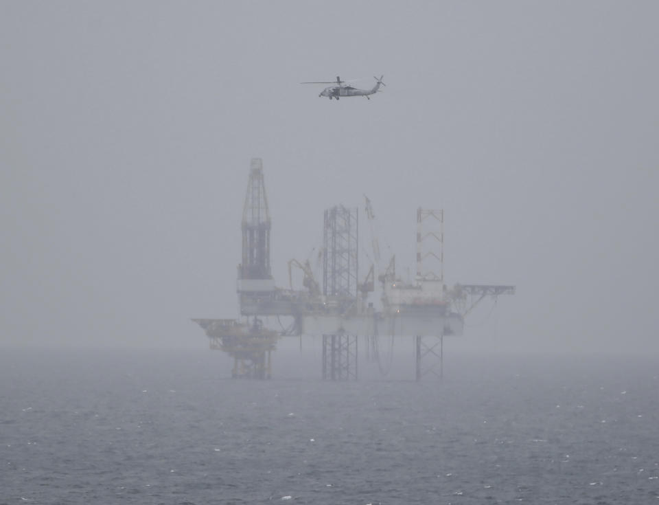 In this Tuesday, March 21, 2017 photograph, a U.S. Navy helicopter flies over an Iranian offshore oil rig as the USS George H.W. Bush travels through the Strait of Hormuz. The arrival of the nuclear-powered aircraft carrier to the Persian Gulf marks the first such deployment under new U.S. President Donald Trump. (AP Photo/Jon Gambrell)