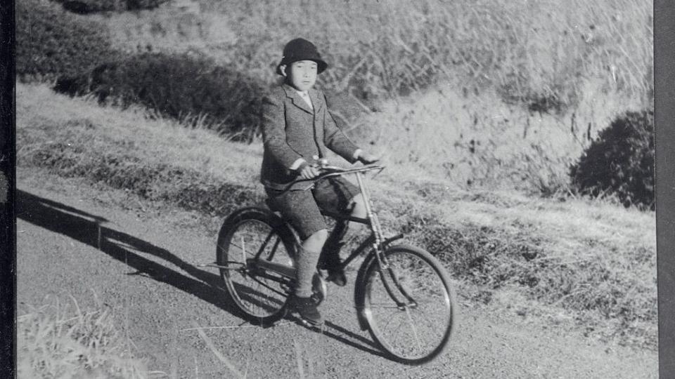 crown prince akihito riding bicycle on palace grounds
