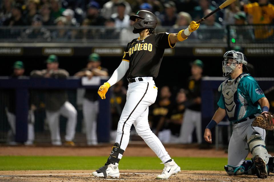 San Diego Padres' Fernando Tatis Jr., left, watches his solo home run during the first inning of a spring training baseball game against the Seattle Mariners, Friday, March 17, 2023, in Peoria, Ariz. (AP Photo/Abbie Parr)