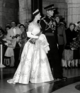 <p>Wearing a dress designed for her by Norman Hartnell for her coronation ceremony, the Queen looked as regal as could be on Prince Philip’s arm at the opening of the Canadian parliament in Canada. <i>[Photo: Rex]</i> </p>