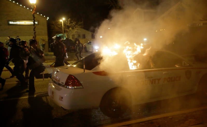 A police vehicle is vandalised and set on fire after. Picture: AP