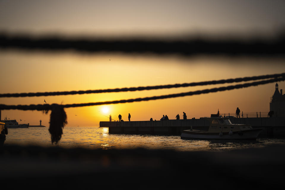 Fishermen casts their lines into the Bosphorus on the Kadikoy sea promenade as the sun sets in Istanbul, Turkey, Monday, March 4, 2024. (AP Photo/Francisco Seco)