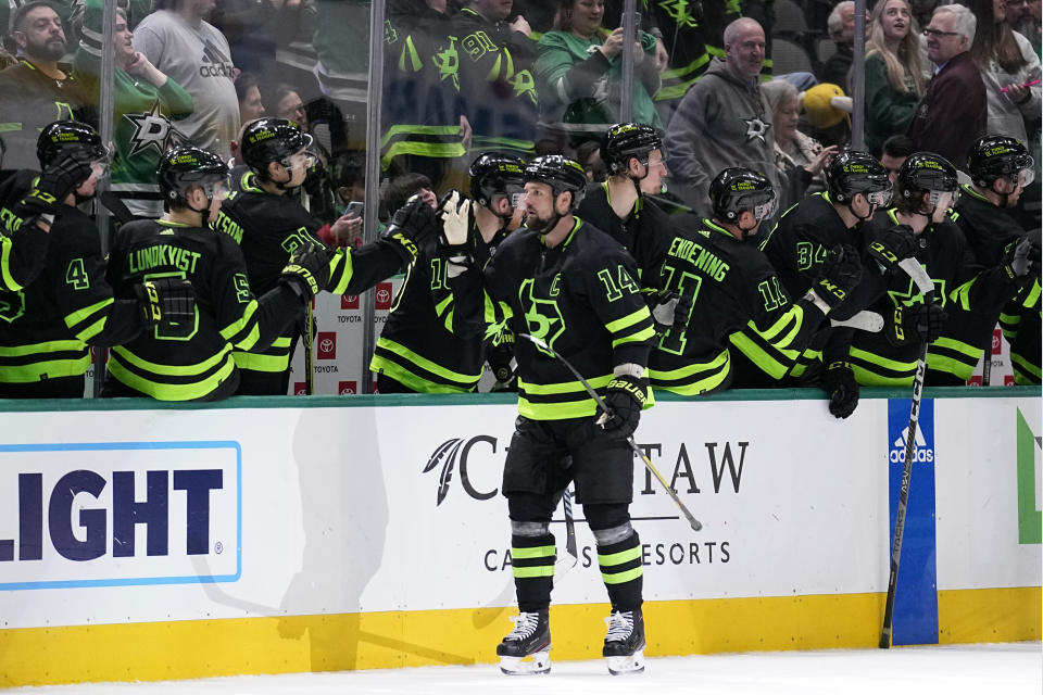 Dallas Stars left wing Jamie Benn (14) celebrates at the bench after scoring in the second period of an NHL hockey game against the Tampa Bay Lightning, Saturday, Feb. 11, 2023, in Dallas. (AP Photo/Tony Gutierrez)