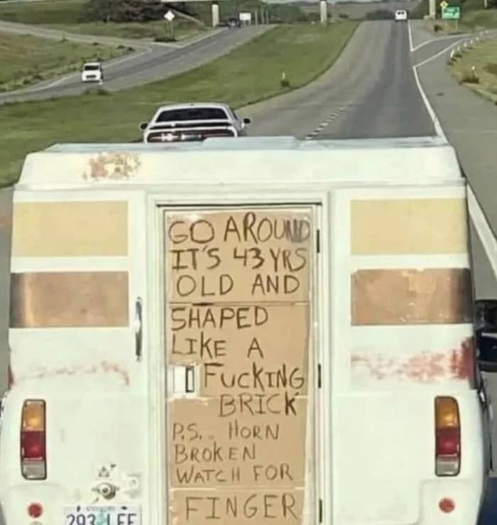 Sign on old truck says, Go around, it's 43 years old and shaped like a brick. PS, horn broken, watch for finger