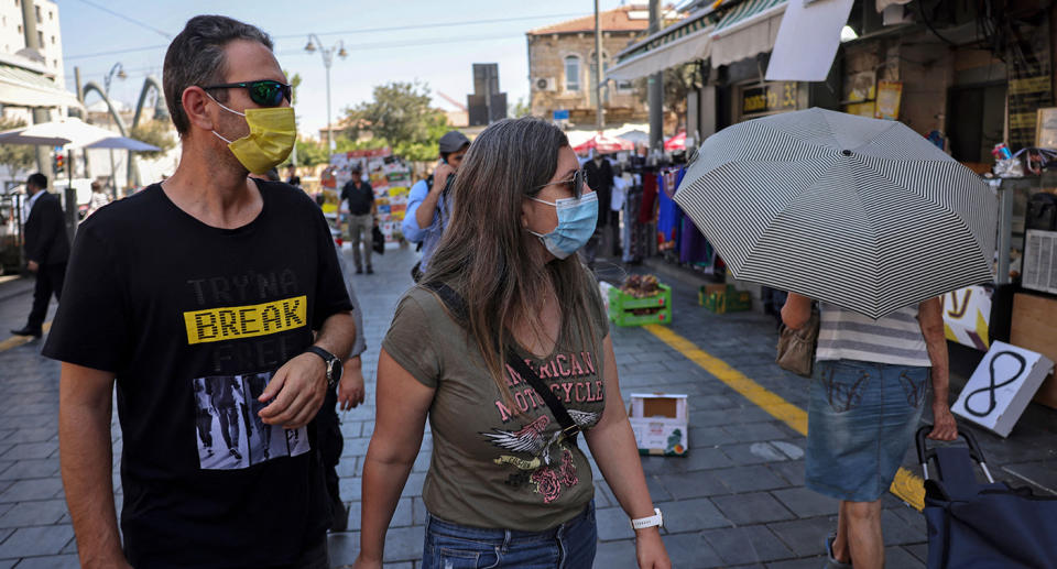 People wearing medical masks walk about at a market in the centre of Jerusalem on August 5, 2021. -