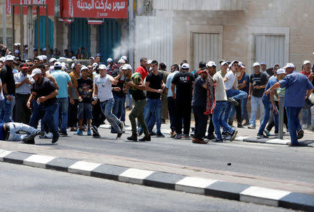 Palestinian protesters react to water canon and tear gas fired by Israeli troops during clashes in the West Bank city of Bethlehem July 21, 2017. REUTERS/Mussa Qawasma