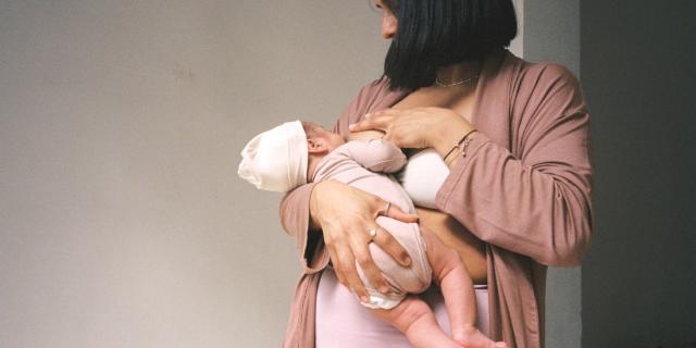 African Mother Breastfeeding Baby In Hospital Room by Stocksy