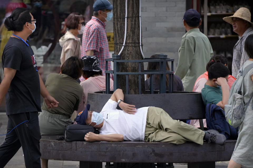 A man wearing a face mask to protect against COVID-19 rests on a bench at a tourist shopping street in Beijing, Tuesday, Aug. 3, 2021. Chinese authorities announced Tuesday mass coronavirus testing in Wuhan as an unusually wide series of COVID-19 outbreaks reached the city where the disease was first detected in late 2019. The current outbreaks, while still in the hundreds of cases in total, have spread much more widely than previous ones, reaching multiple provinces and cities including the capital, Beijing. (AP Photo/Mark Schiefelbein)