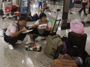 Mainland Chinese passengers eat lunch while waiting at Hong Kong Airport, as flights are cancelled in anticipation of typhoon Usagi, September 22, 2013. Hong Kong was bracing on Sunday for this year's most powerful typhoon, with government meteorologists warning of severe flooding created by a double whammy of powerful winds and exceptionally high tides. Typhoon Usagi, the strongest storm to hit the Western Pacific this year, is expected to hit the Asian financial center late on Sunday and early on Monday. REUTERS/Bobby Yip (CHINA - Tags: ENVIRONMENT TRANSPORT BUSINESS)