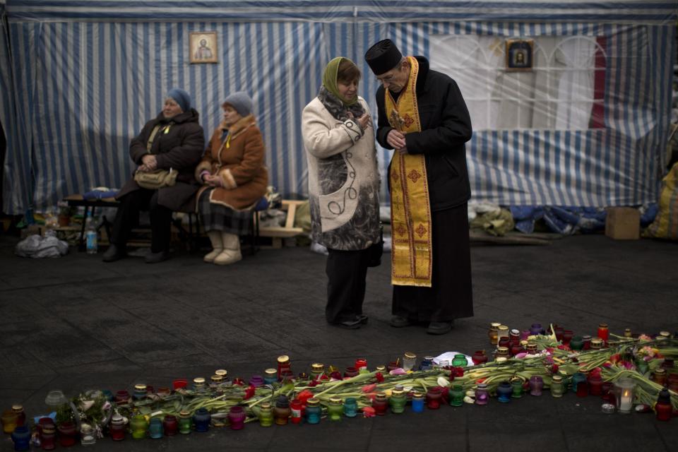 A priest hears a woman's confession at an improvised church in Kiev's Independence Square, Saturday, March 1, 2014. The pro-Russian prime minister of Ukraine's restive Crimea is claiming control of all military forces, police and other security services in the region. In a statement reported by local and Russian news agencies on Saturday, Sergei Aksenov declares that the armed forces, the police, the national security service and border guards will answer only to his orders. He says that any commanders who don't agree should leave their posts. (AP Photo/Emilio Morenatti)