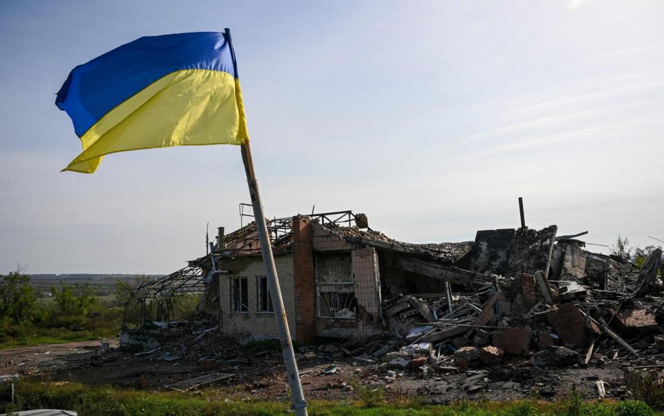 A Ukrainian national flag is displayed in front of a destroyed house near Izyum in eastern Ukraine - JUAN BARRETO/AFP