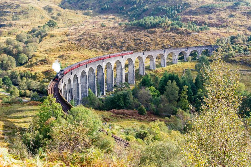 Glenfinnan Railway Viaduct in Scotland, with a steam train crossing. The viaduct was built in 1901.