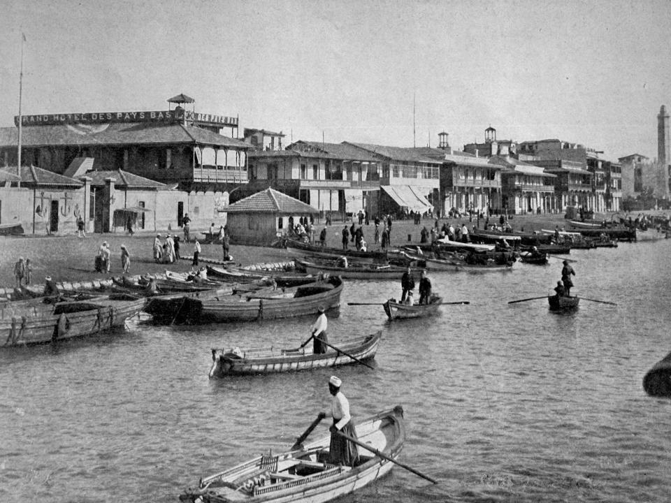 People in small boats in front of buildings at Port Said on the Suez Canal