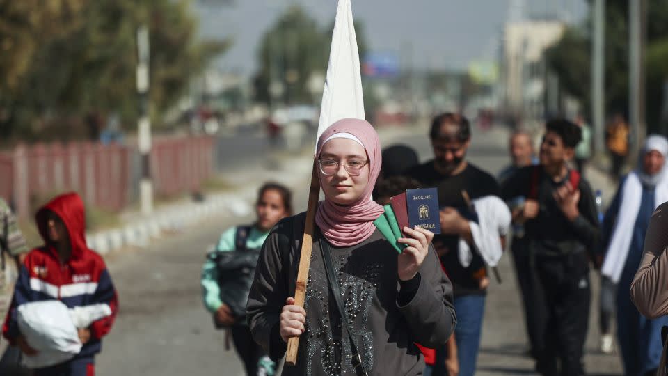 A Palestinian woman carries her passport and ID as she flees south on November 7. - Ahmed Zakot/Sipa USA/AP