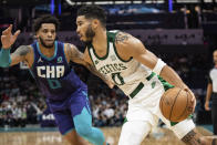 Boston Celtics forward Jayson Tatum, right, drives to the basket while guarded by Charlotte Hornets forward Miles Bridges, left, during the first half of an NBA basketball game in Charlotte, N.C., Monday, Oct. 25, 2021. (AP Photo/Jacob Kupferman)