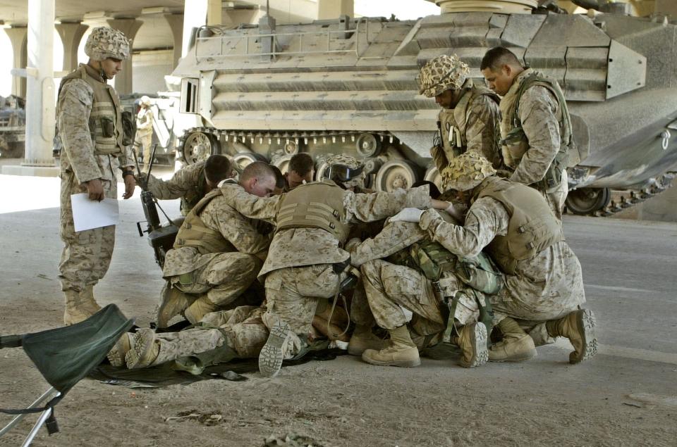 FILE - U.S. Marines pray over a fallen comrade at a first aid point after he died from wounds suffered in fighting in Fallujah, Iraq, April 8, 2004. (AP Photo/Murad Sezer, File)