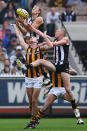 Ben Reid of the Magpies jumps for a high mark over David Hale of the Hawks but sustains a leg injury when landing on his right leg.