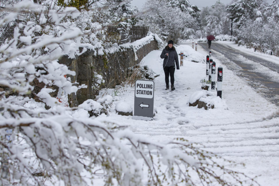 A woman arrives at a polling station, after snowfall, in the village of Farr, near Inverness, Scotland, Thursday May 6, 2021. Scots are heading to the polls to elect the next Scottish Government - though the coronavirus pandemic means it could be more than 48 hours before all the results are counted. (Paul Campbell/PA via AP)