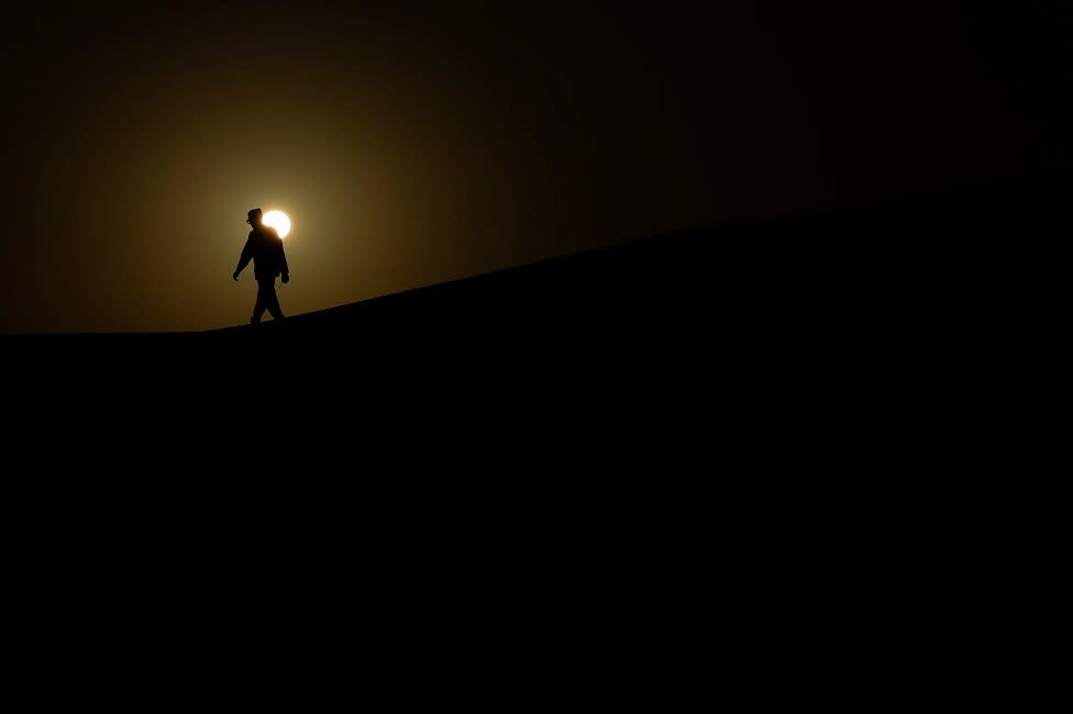 A soldier from the Sahrawi Popular Liberation Army walks along a dune.