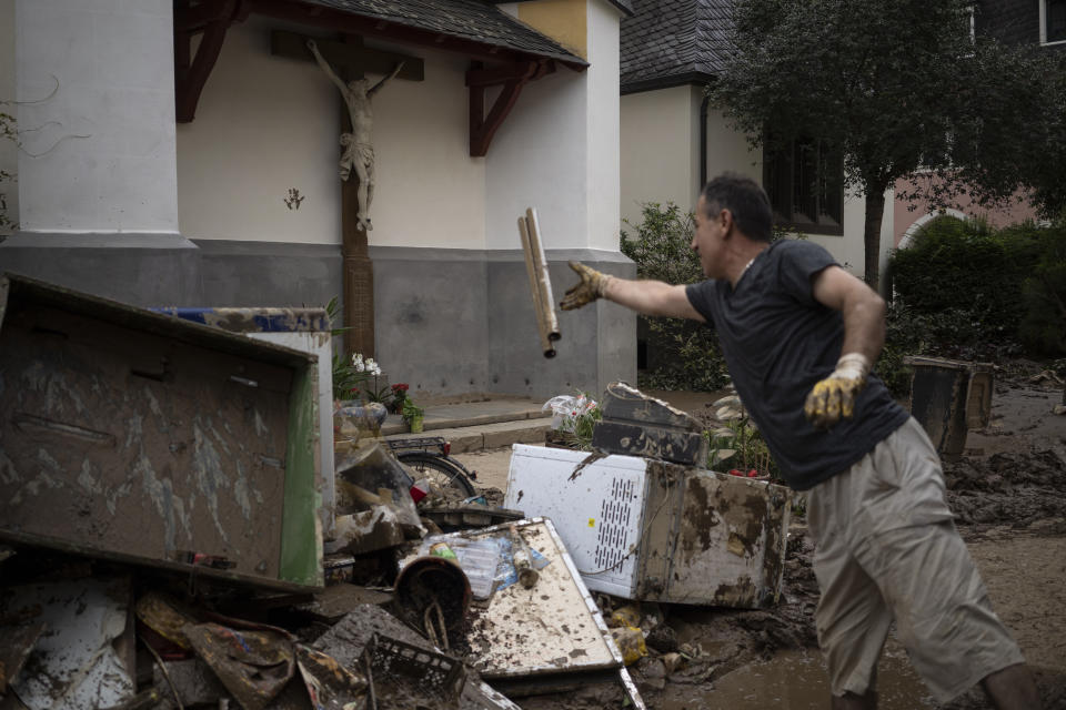 A man throws away debris from the flood disaster in Bad Neuenahr-Ahrweiler, Germany, Monday July 19, 2021. More than 180 people died when heavy rainfall turned tiny streams into raging torrents across parts of western Germany and Belgium, and officials put the death toll in Ahrweiler county alone at 110. (AP Photo/Bram Janssen)