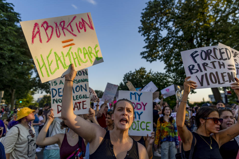 Protesters holding signs advocating for abortion rights. One sign reads "Abortion = Healthcare."